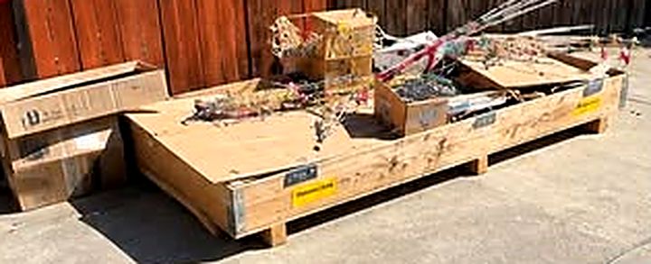 Before: a large wooden crate, boxes and debris on a concrete patio by a fence